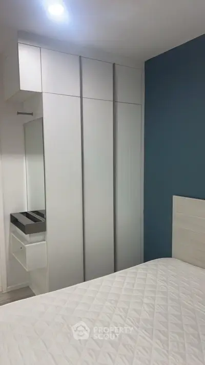 Modern bedroom with sleek white wardrobe and blue accent wall, perfect for stylish living.