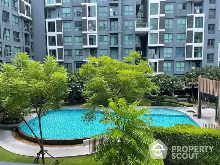 Luxurious apartment complex with a large, inviting swimming pool surrounded by lush greenery and modern architectural design.