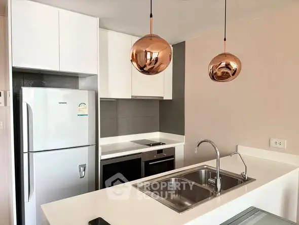 Modern kitchen with sleek design, featuring stainless steel appliances and stylish pendant lights.