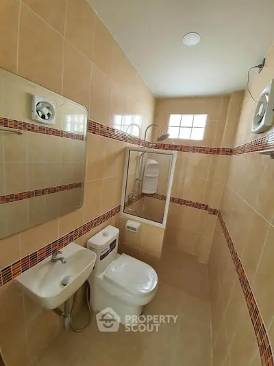 Compact bathroom with modern fixtures and stylish tile design, featuring a shower and toilet.
