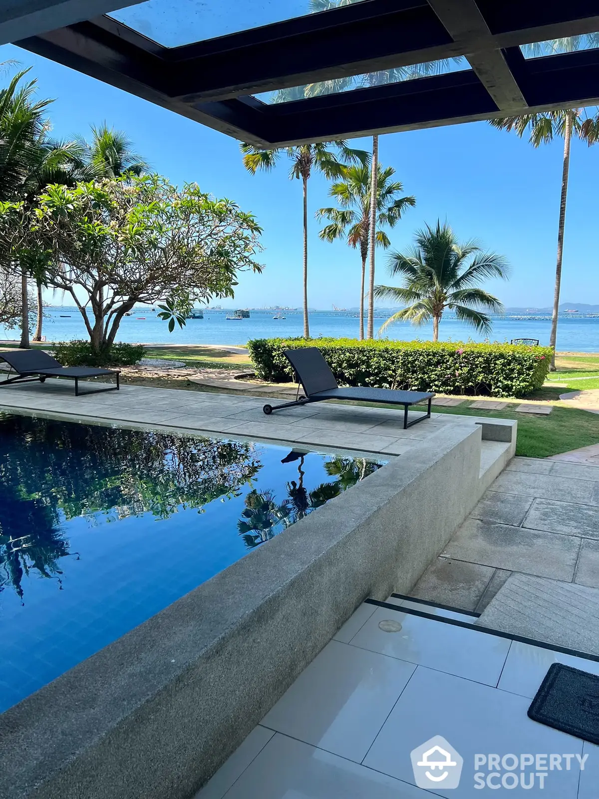 Luxurious beachfront villa with infinity pool and panoramic ocean view, surrounded by lush tropical greenery and serene landscape.