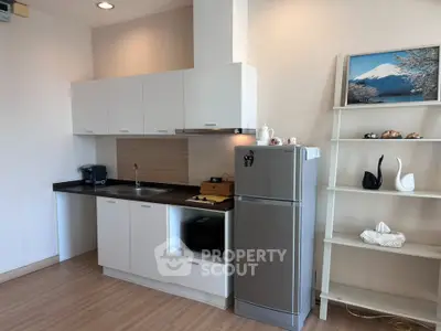 Modern kitchen with sleek cabinets and stainless steel fridge in cozy apartment.