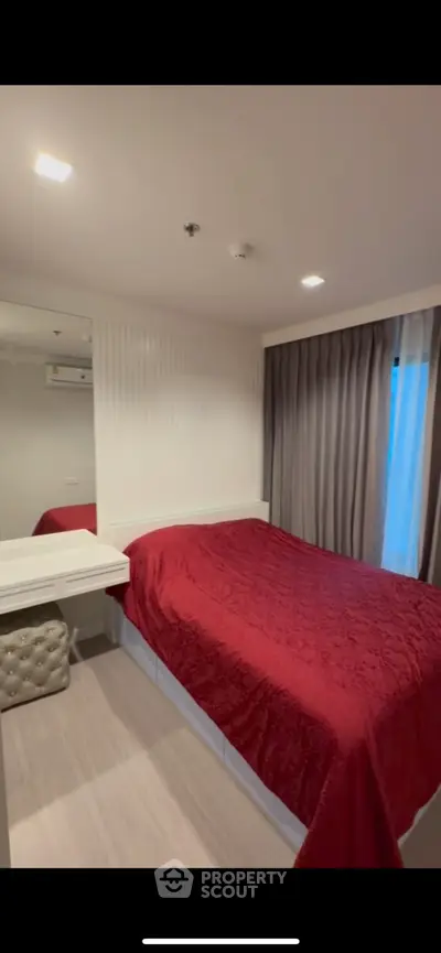 Cozy bedroom with red bedding and elegant decor, featuring a large mirror and soft lighting for a warm ambiance.