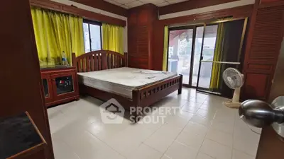 Spacious bedroom with wooden furniture and large windows for natural light.