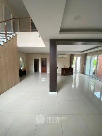 Spacious modern living room with glossy tiles and elegant staircase
