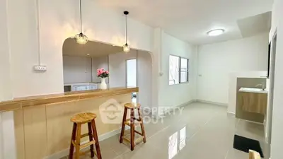 Modern open-plan kitchen with breakfast bar and stools, bright and airy space.