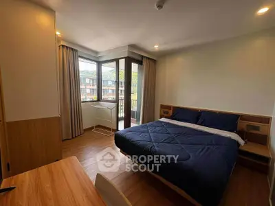 Spacious bedroom with large windows and scenic view, featuring modern furnishings and natural light.