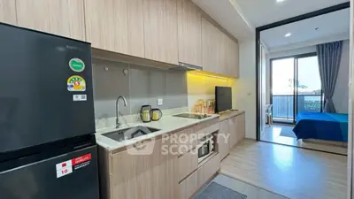 Modern kitchen with sleek cabinetry and open layout leading to a cozy bedroom with balcony view.