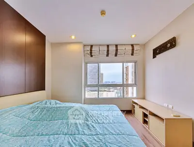 Spacious bedroom with city view and modern furnishings in a high-rise apartment.
