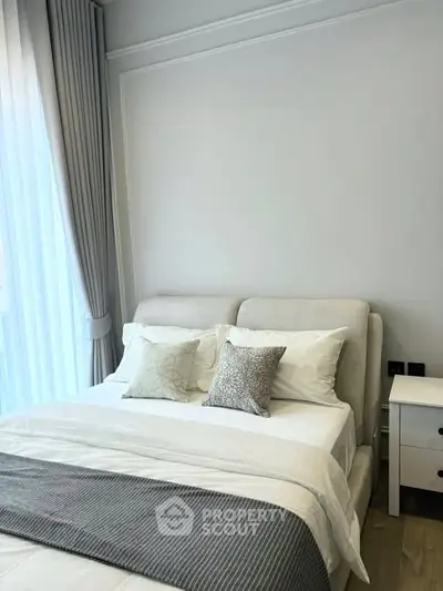 Elegant bedroom with modern decor and natural light, featuring plush bedding and stylish curtains.