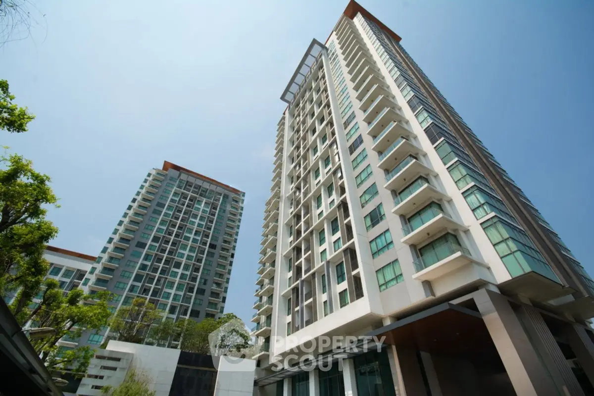 Modern high-rise residential buildings with glass facades and lush greenery.