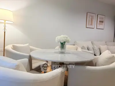 Elegant living room with modern white furniture and round marble table, perfect for stylish gatherings.