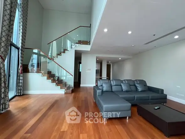 Spacious modern living room with elegant staircase and sleek furniture in luxury apartment.