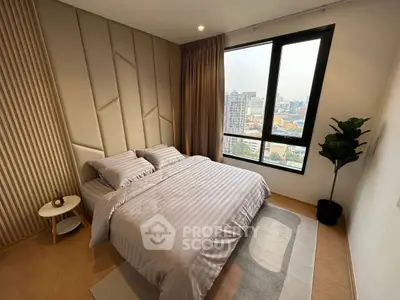 Modern bedroom with city view, featuring stylish decor and large window for natural light.