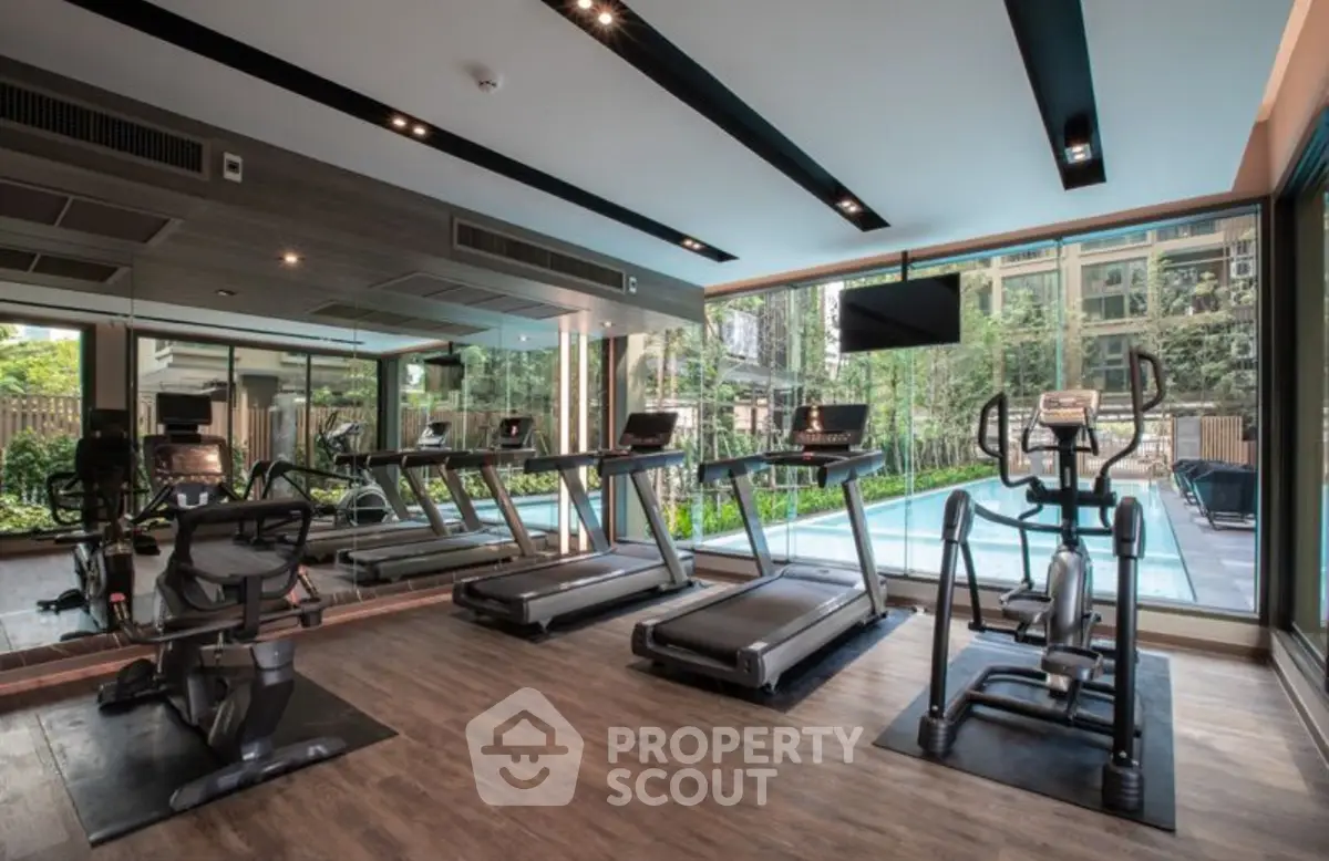 Modern gym with state-of-the-art equipment and pool view in luxury residential building.