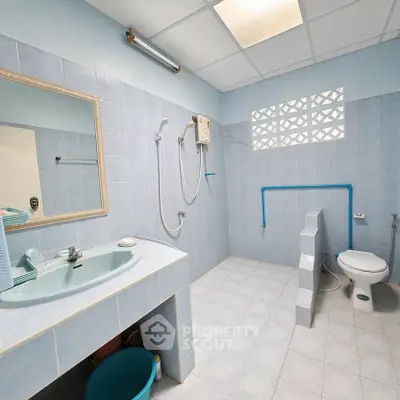 Spacious bathroom with modern fixtures and tiled walls, featuring a shower and toilet.