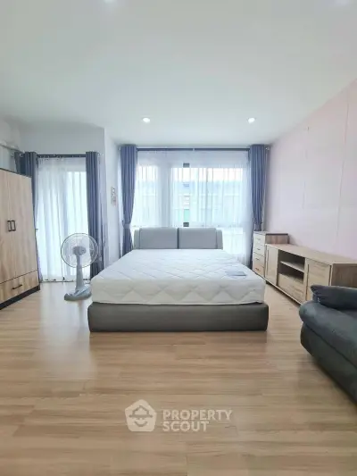 Spacious bedroom with modern furnishings and large windows for natural light.
