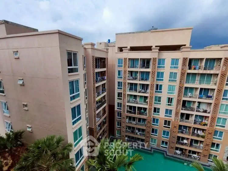 Stunning view of modern apartment complex with pool and lush greenery.