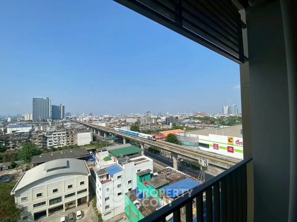 Stunning cityscape view from a high-rise balcony overlooking urban skyline and railway.
