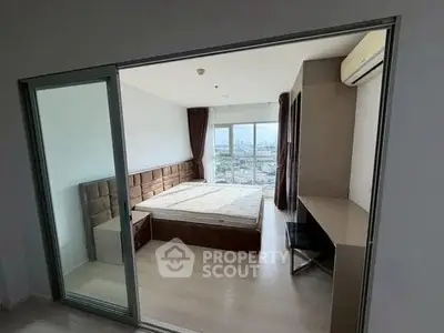 Spacious bedroom with city view, featuring modern furniture and large windows for natural light.