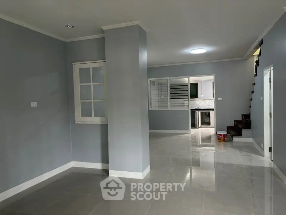 Spacious open-plan living area with modern staircase and sleek kitchen view.
