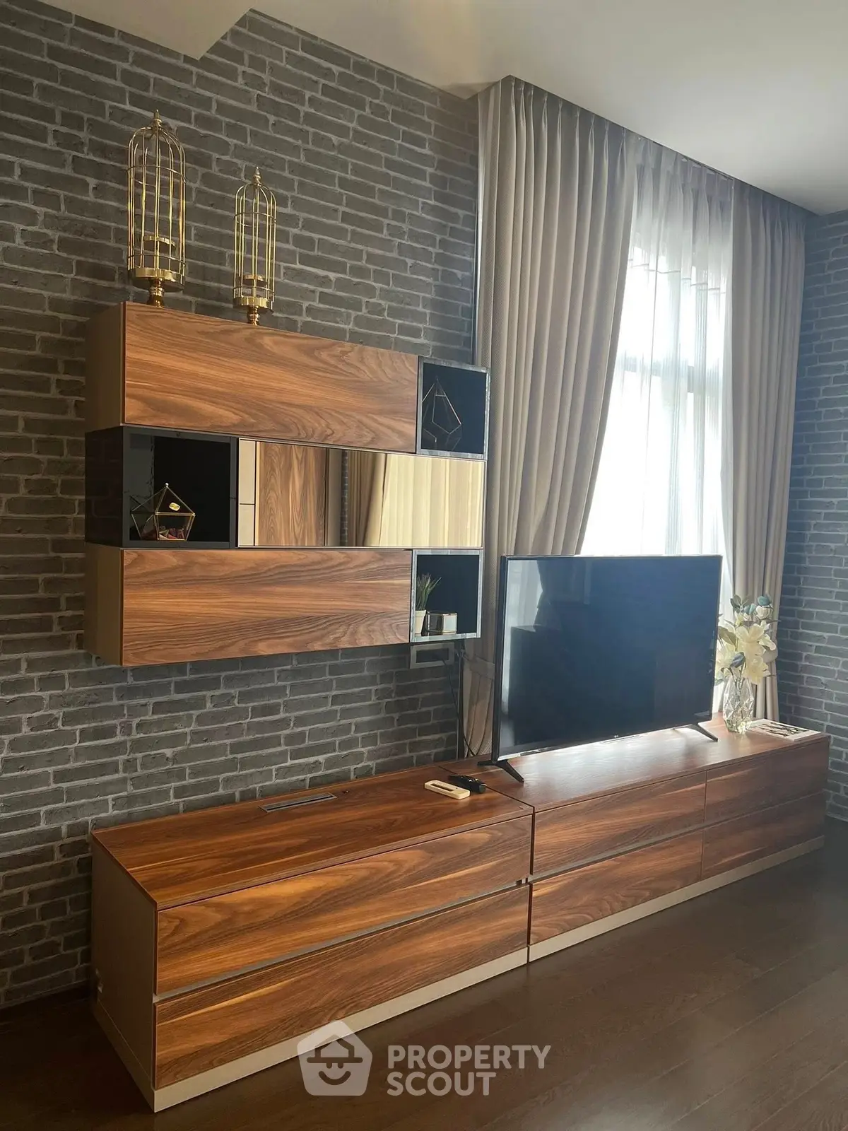 Stylish living room with modern wooden TV unit and elegant brick wall design.