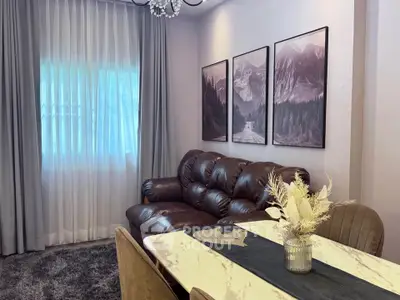 Elegant living room with plush leather sofa, chic decor, and natural light through sheer curtains.