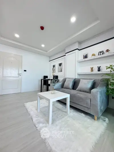 Modern living room with sleek gray sofa, white coffee table, and stylish decor on a plush rug.