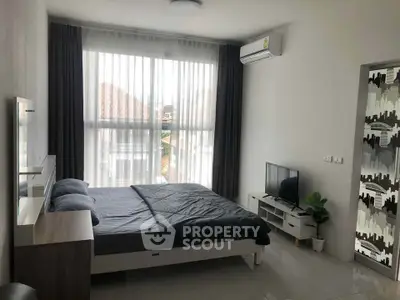 Modern bedroom with large window, stylish decor, and natural light in a contemporary apartment.