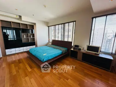 Spacious bedroom with modern furnishings and city view, featuring hardwood floors and ample natural light.