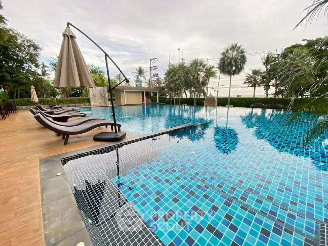 Luxurious outdoor swimming pool with elegant loungers and umbrellas, surrounded by lush greenery.