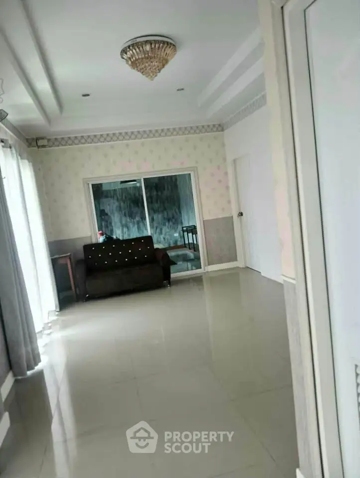 Spacious living room with elegant chandelier and large windows for natural light.
