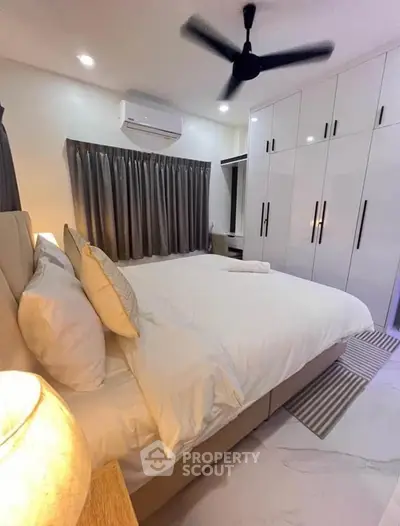 Modern bedroom with white decor, spacious wardrobe, and ceiling fan