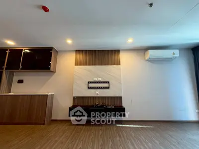 Modern living room with wood flooring, wall-mounted TV setup, and air conditioning.