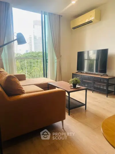 Modern living room with large window and city view, featuring stylish furniture and a flat-screen TV.