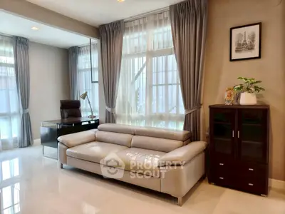 Elegant living room with modern sofa and stylish decor, featuring large windows and abundant natural light.