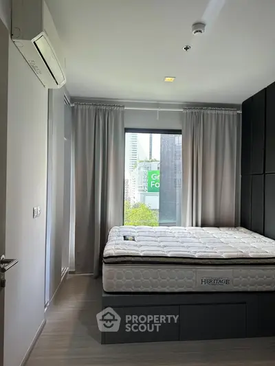 Modern bedroom with large window and city view, featuring sleek design and natural light.