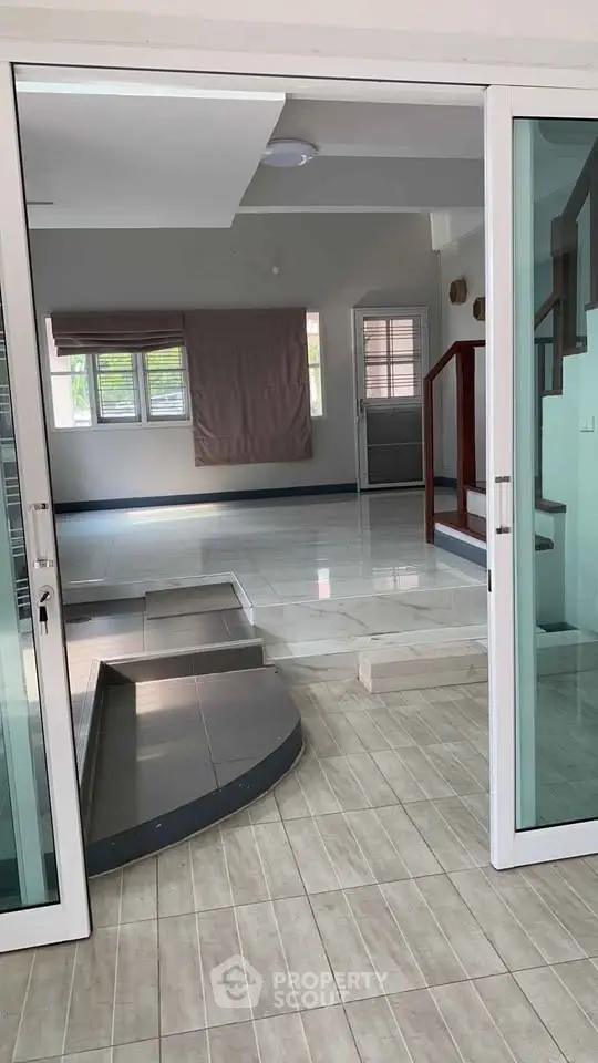Spacious modern interior with glass doors and stylish staircase, perfect for contemporary living.