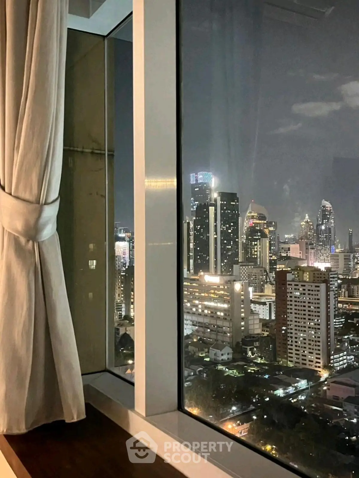 Stunning cityscape view from a high-rise window at night, showcasing vibrant urban skyline.