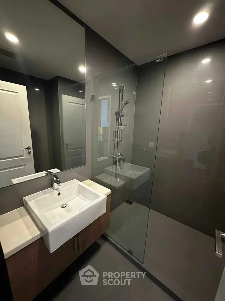 Modern bathroom with sleek glass shower and stylish sink in contemporary apartment.
