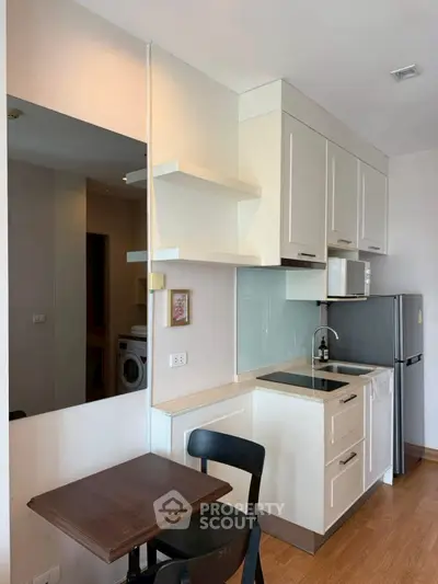 Modern compact kitchen with sleek cabinetry and integrated appliances in a cozy apartment setting.