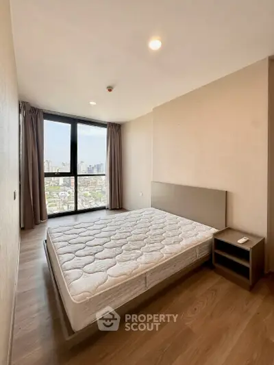 Spacious bedroom with city view, featuring a large window and modern design in a high-rise apartment.
