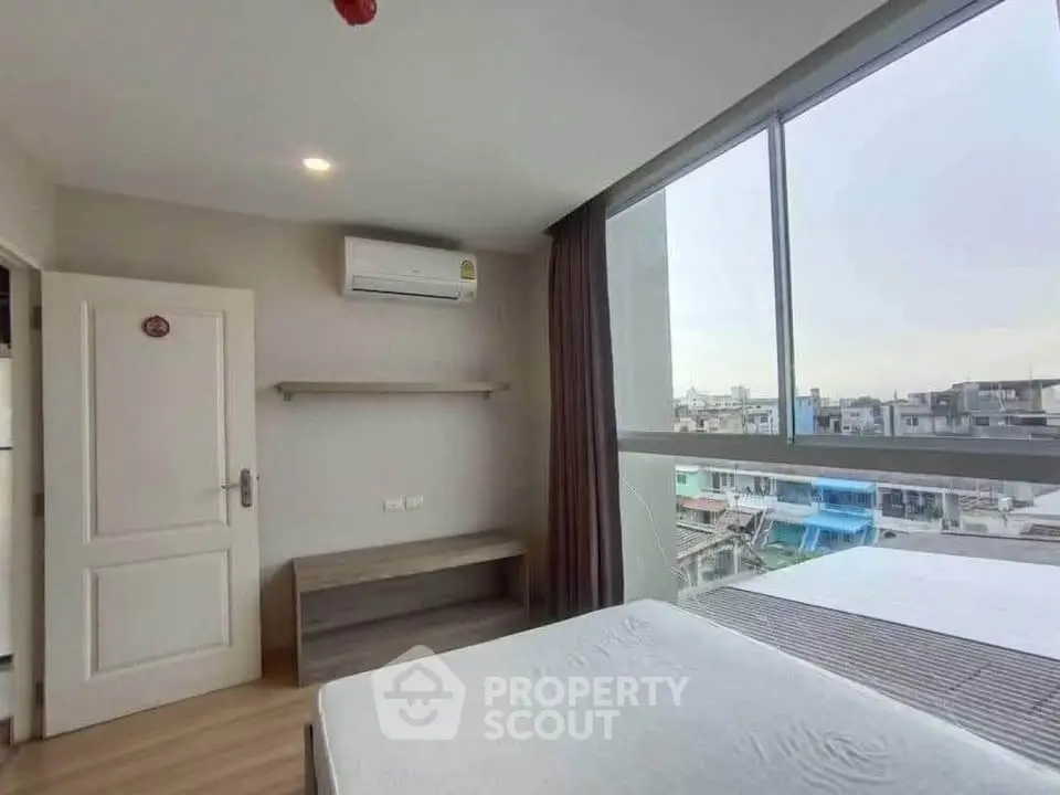 Modern bedroom with large windows offering city views and minimalist decor.