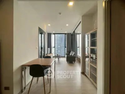 Modern living room with sleek furniture and large windows offering city views.
