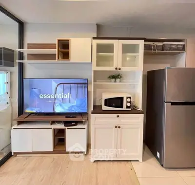 Modern living room with TV, microwave, and fridge in stylish cabinetry