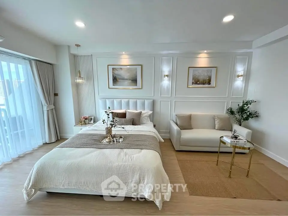 Luxurious bedroom with elegant decor and natural light, featuring a cozy seating area and stylish wall art.