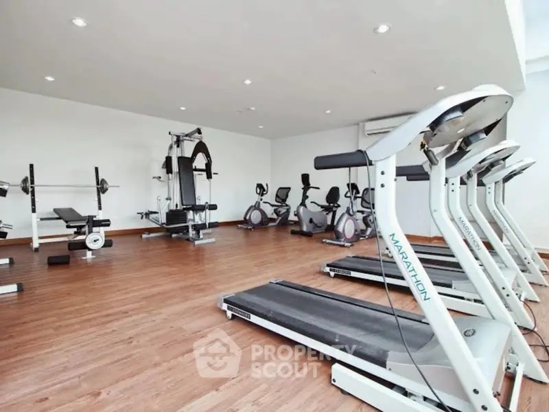 Spacious modern gym with state-of-the-art equipment in luxury apartment complex.