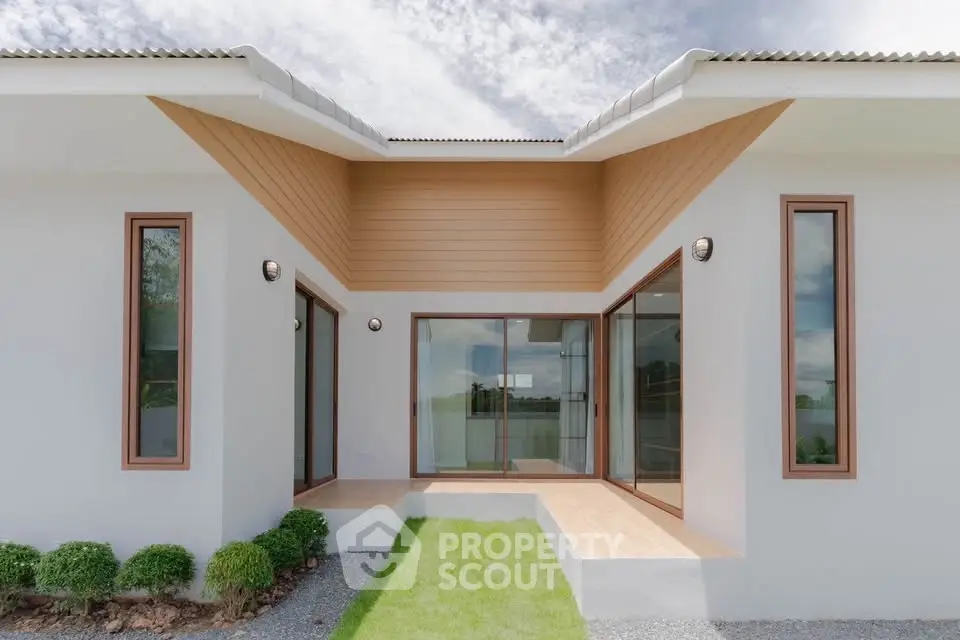 Modern minimalist home exterior with large windows and lush green lawn