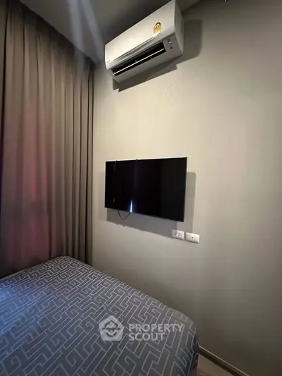 Cozy bedroom with wall-mounted TV and air conditioning unit, perfect for relaxation.