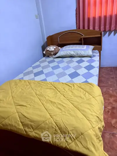 Cozy bedroom with single bed, colorful bedding, and warm lighting.